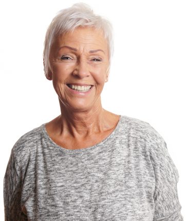 Elderly woman with short grey hair is smiling widely on a white background